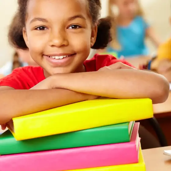 smiling-student-leaning-stacked-books
